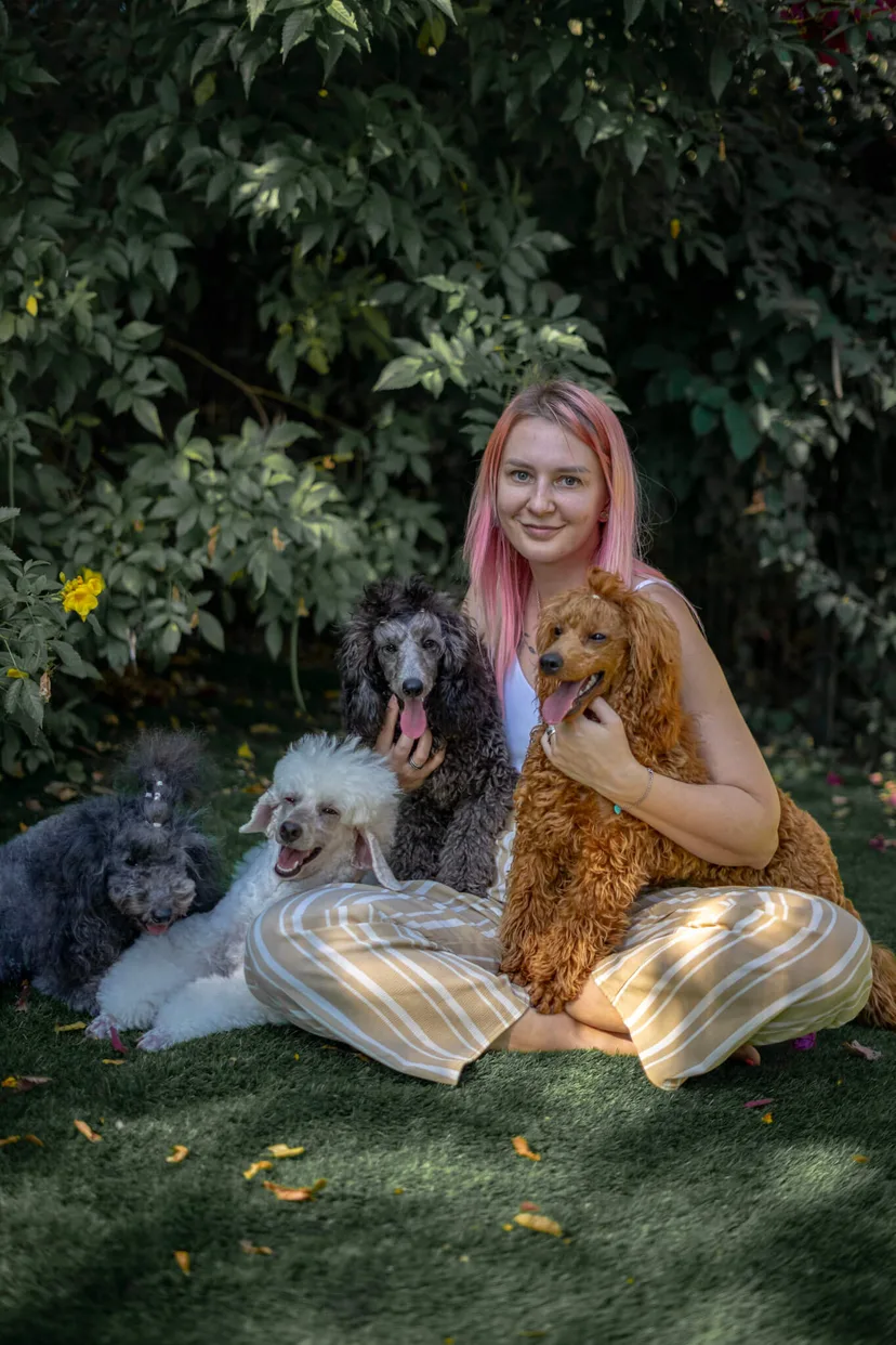 Helen sitting outdoors with her four poodles at Mystic Estate